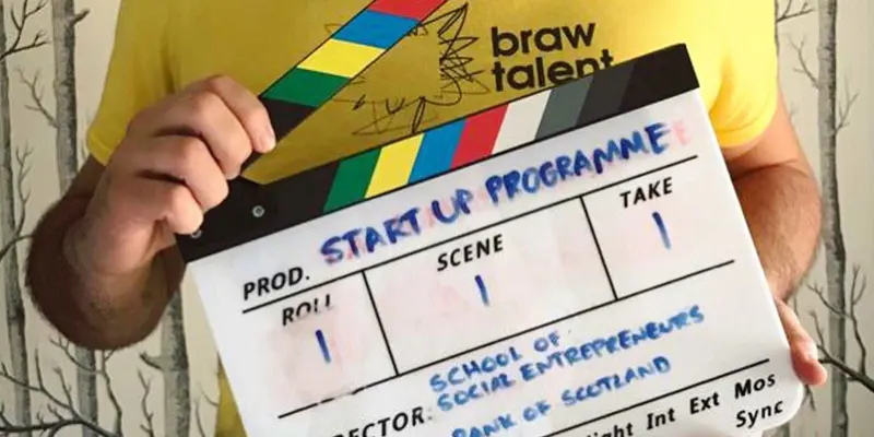Darren holding a clapper board for The Start Up Programme with school of enterprise and The Bank of Scotland.