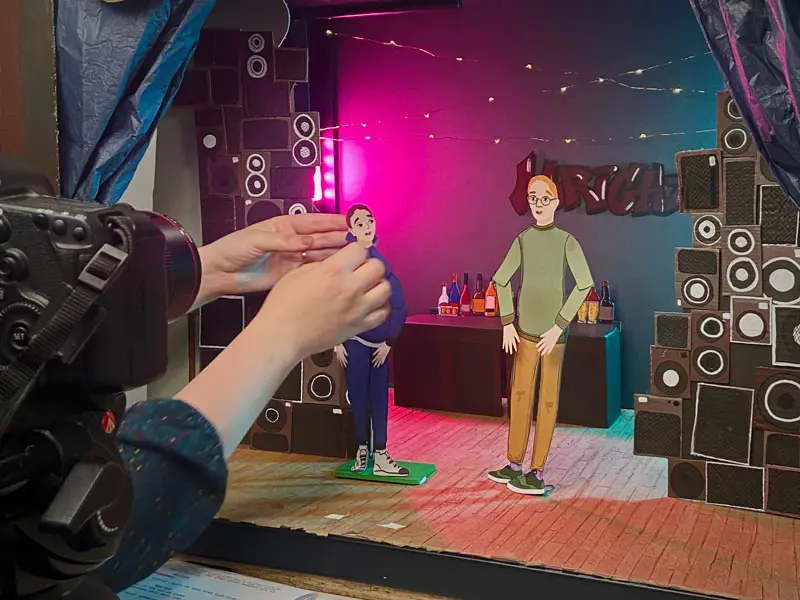 a behind the scenes view of the camera set of for the clan childlaw animation. Lydia makes an adjustment to a character.